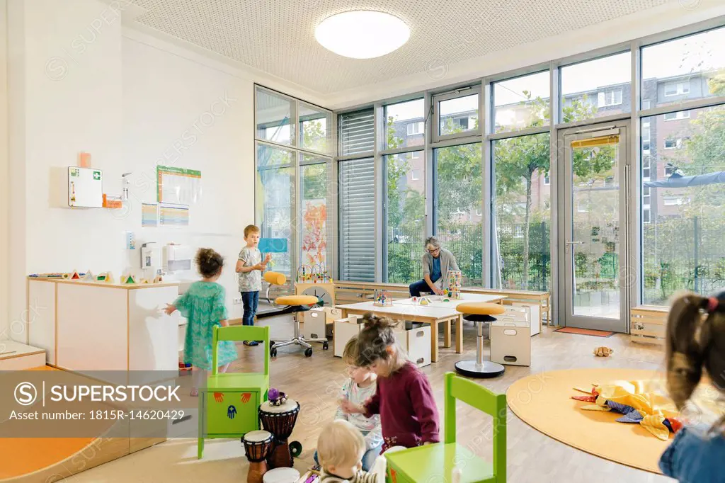Pre-school teacher and children in playing in learning room in kindergarten