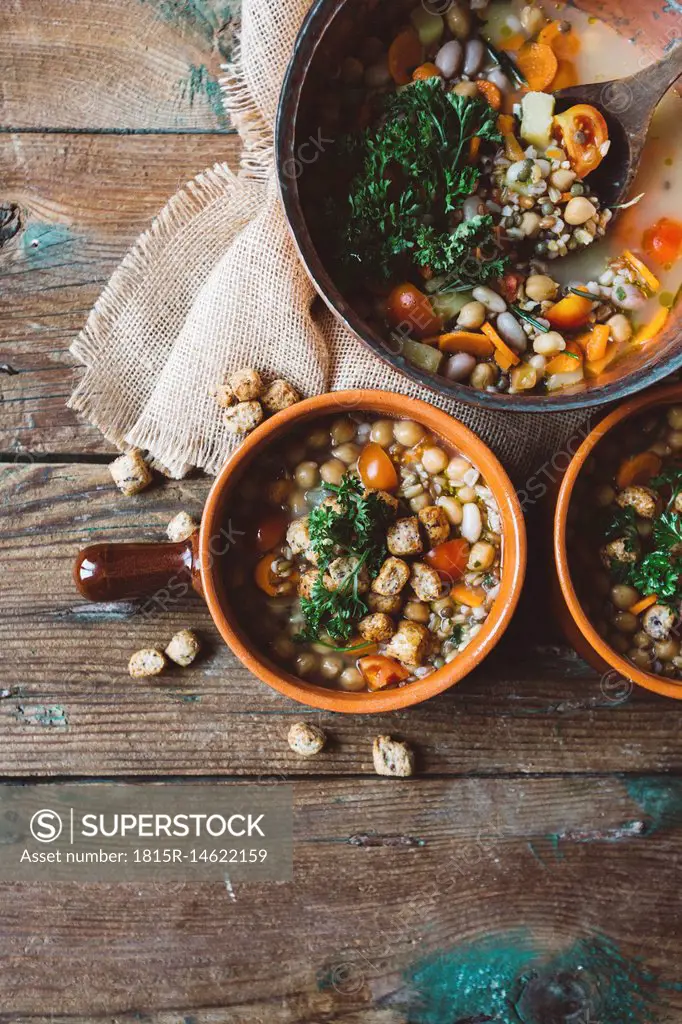 Mediterranean soup in copper pot and terracotta bowls on wood