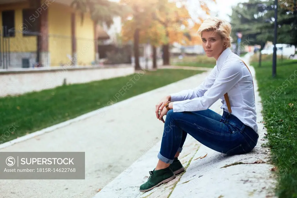 Sad teenage girl sitting at the roadside waiting