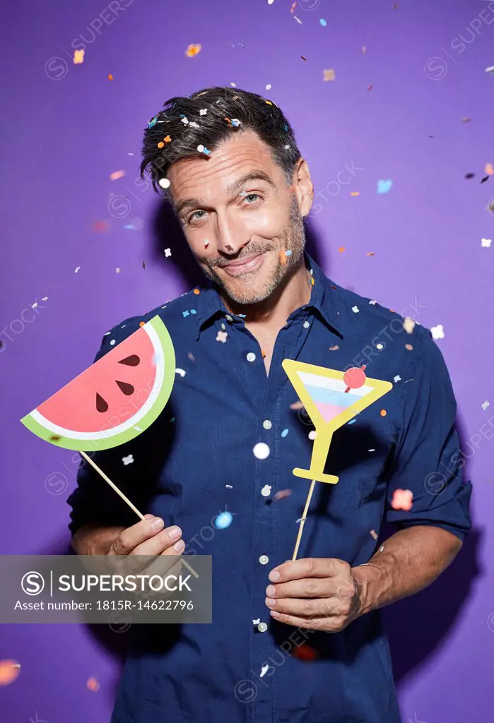 Portrait of smiling man party decoration standing in shower of confetti