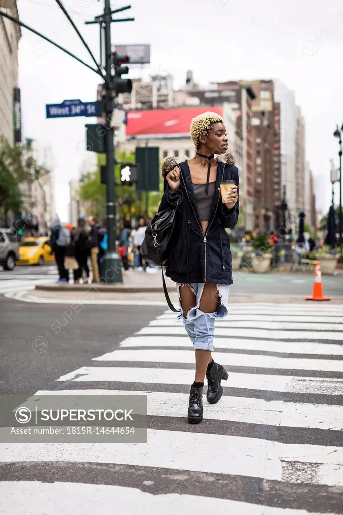 USA, New York City, fashionable young woman with coffee to go crossing the street