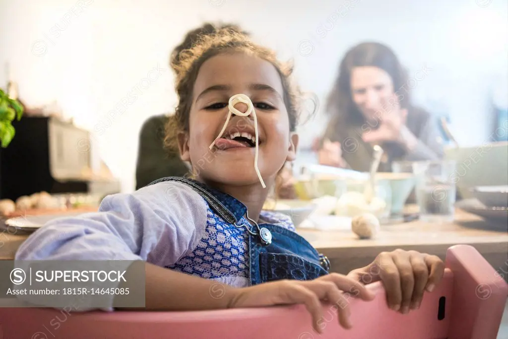 Portrait of a cheeky little girl eating spaghetti