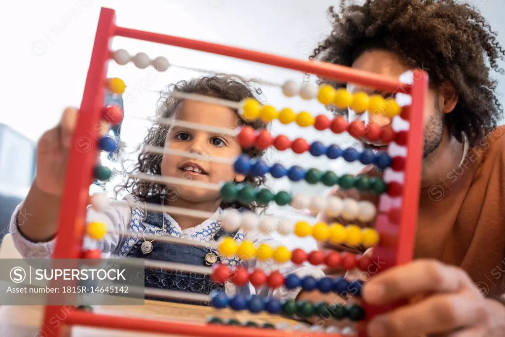 Father sitting at table with his daughter learning to caculate with a slide rule