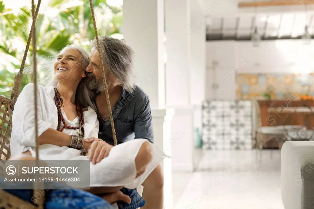 Senior man taking selfie at poolside while his wife is playing the guitar