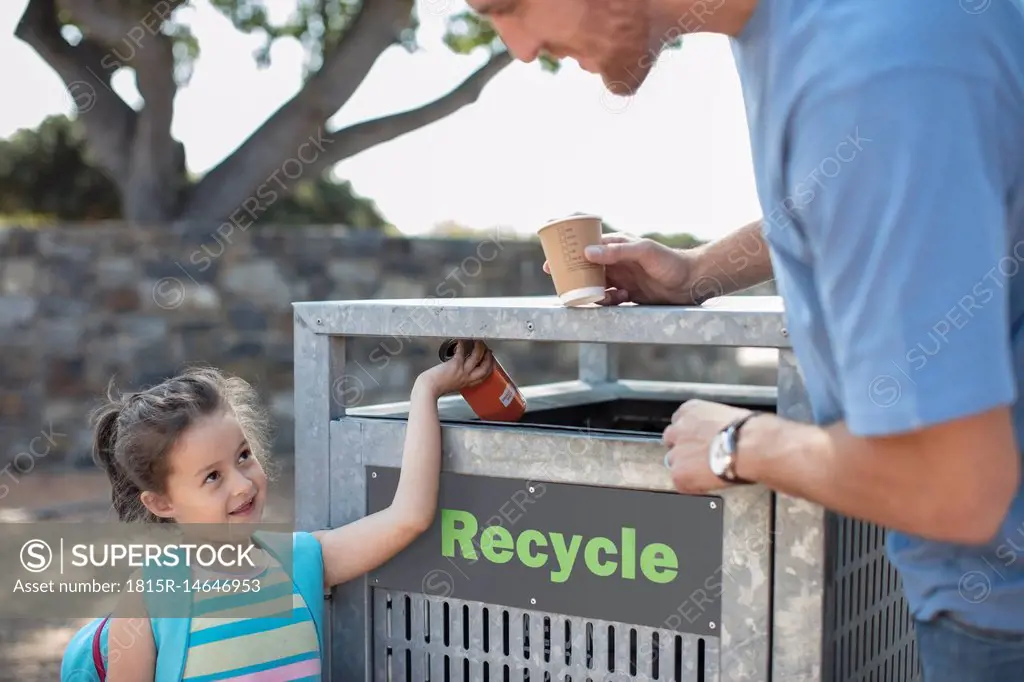 Girl with father putting a drink can in a recycle bin