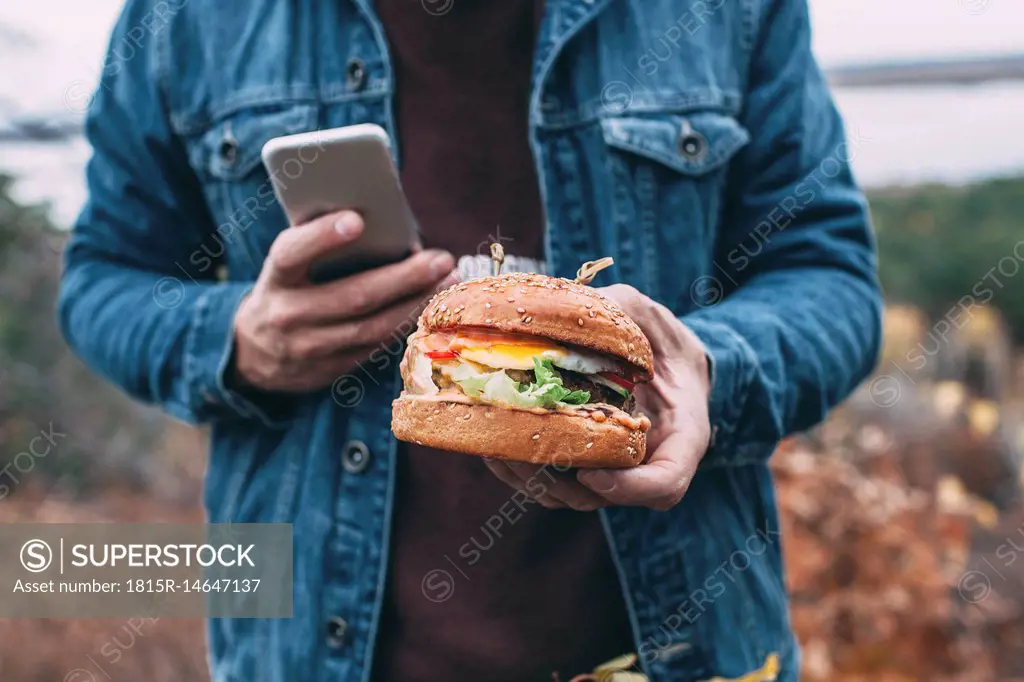 Man with burger and smartphone