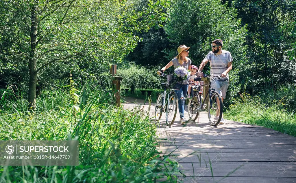 Family pushing bicycles on wooden walkway