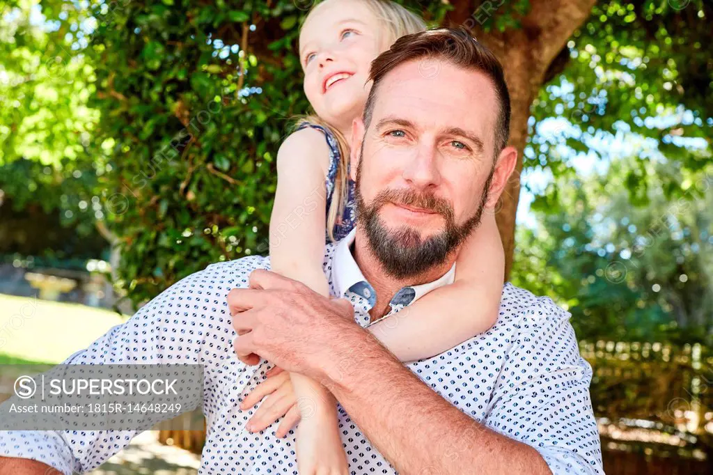 Portrait of smiling father carrying daughter piggyback