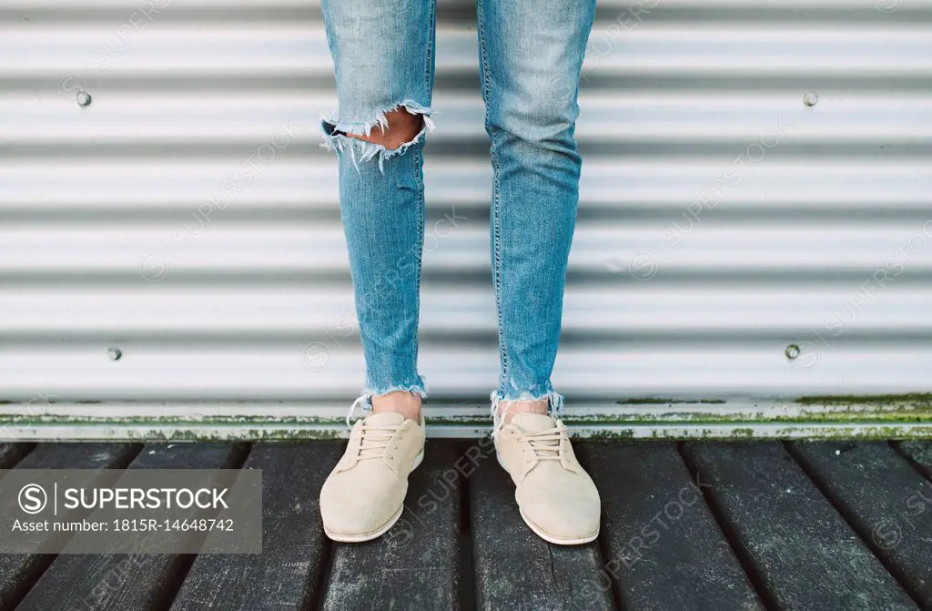 Legs of man wearing torn jeans