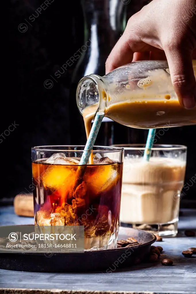 Hand pouring homemade vanilla flavoured coffee creamer into a glas with iced coffee