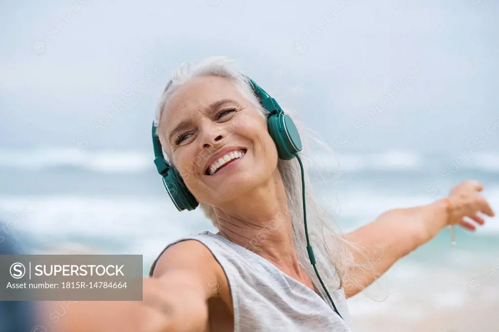 Portrait of beautiful smiling senior woman dancing on beach