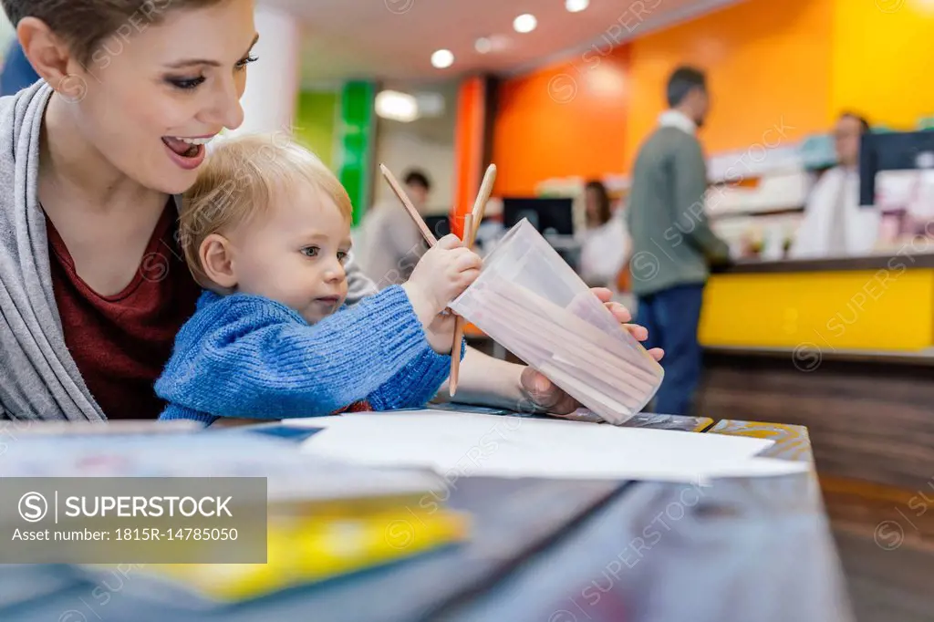 Little boy with mother drawing at table in pharmacy