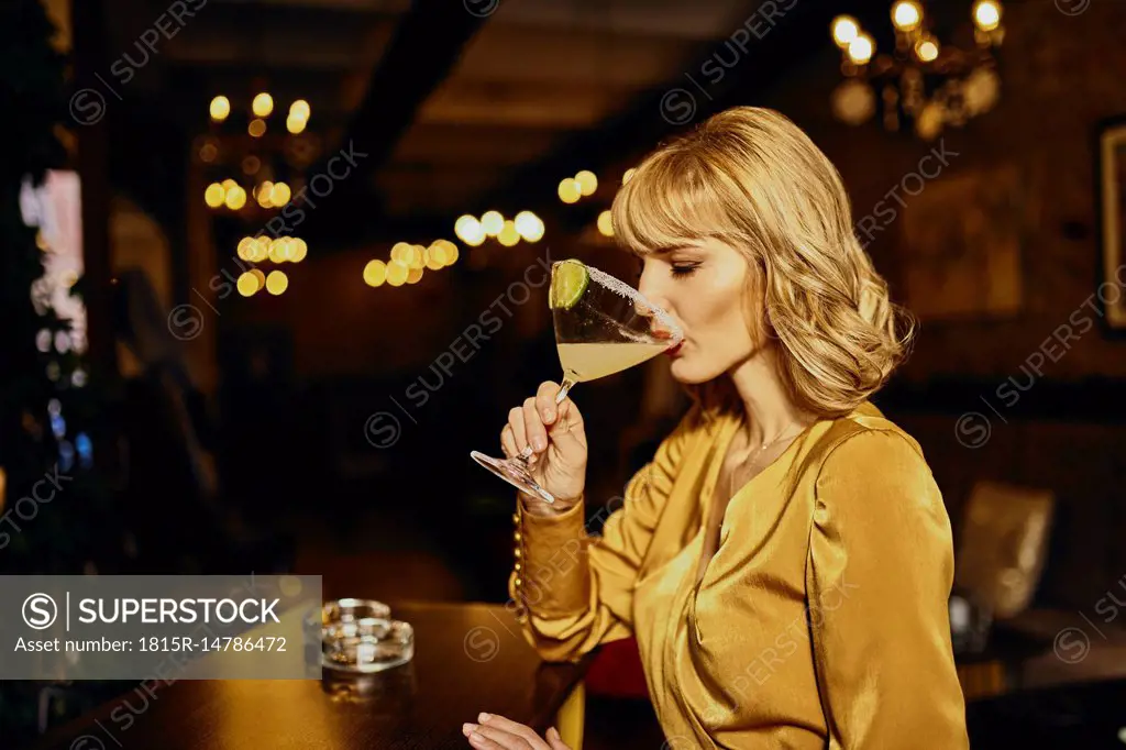 Elegant woman drinking cocktail in a bar