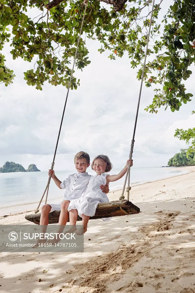 Thailand, Ko Yao Noi, happy boy and little girl on a swing on the beach