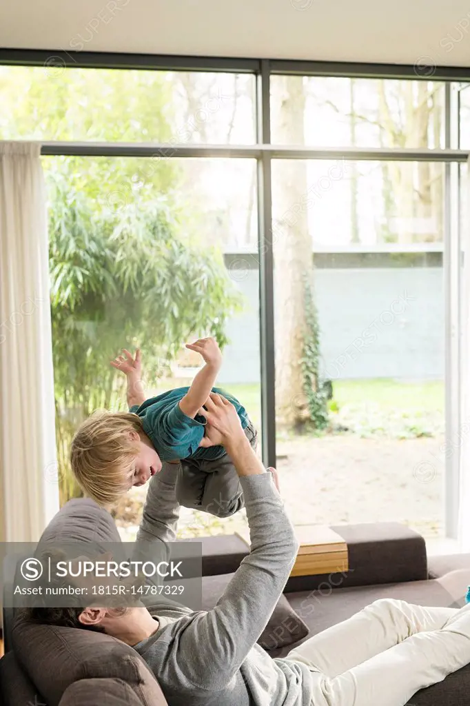 Happy father playing with son on sofa at home