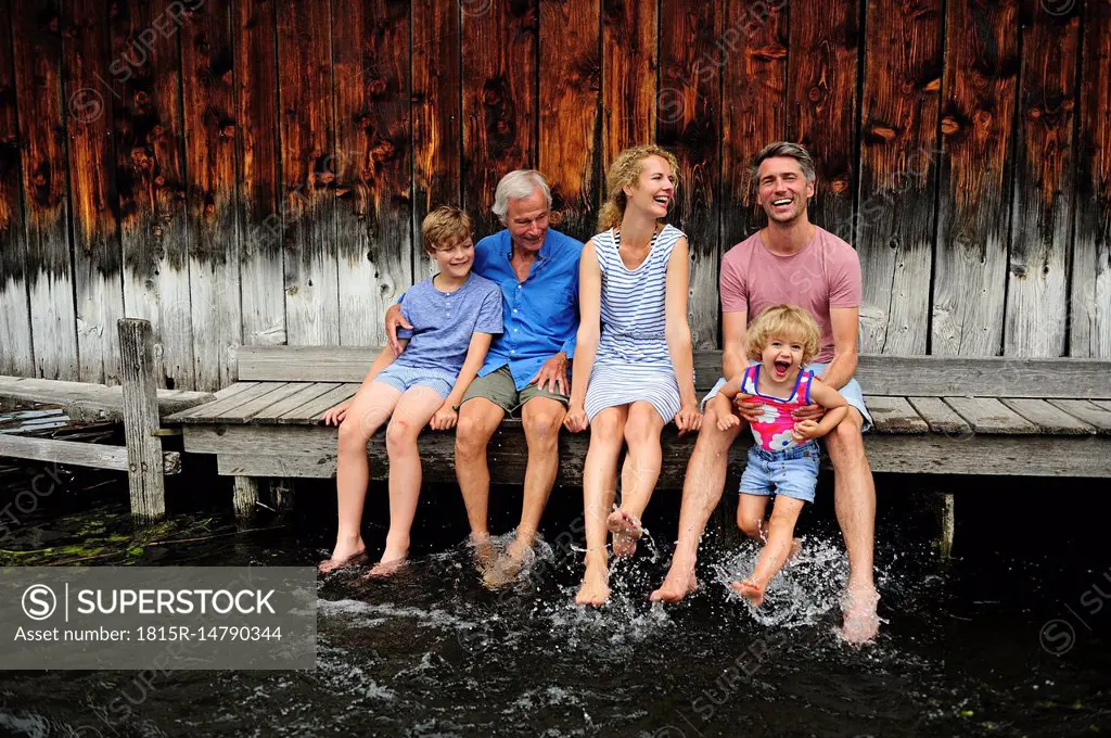 Family sitting together on jetty splashing with water