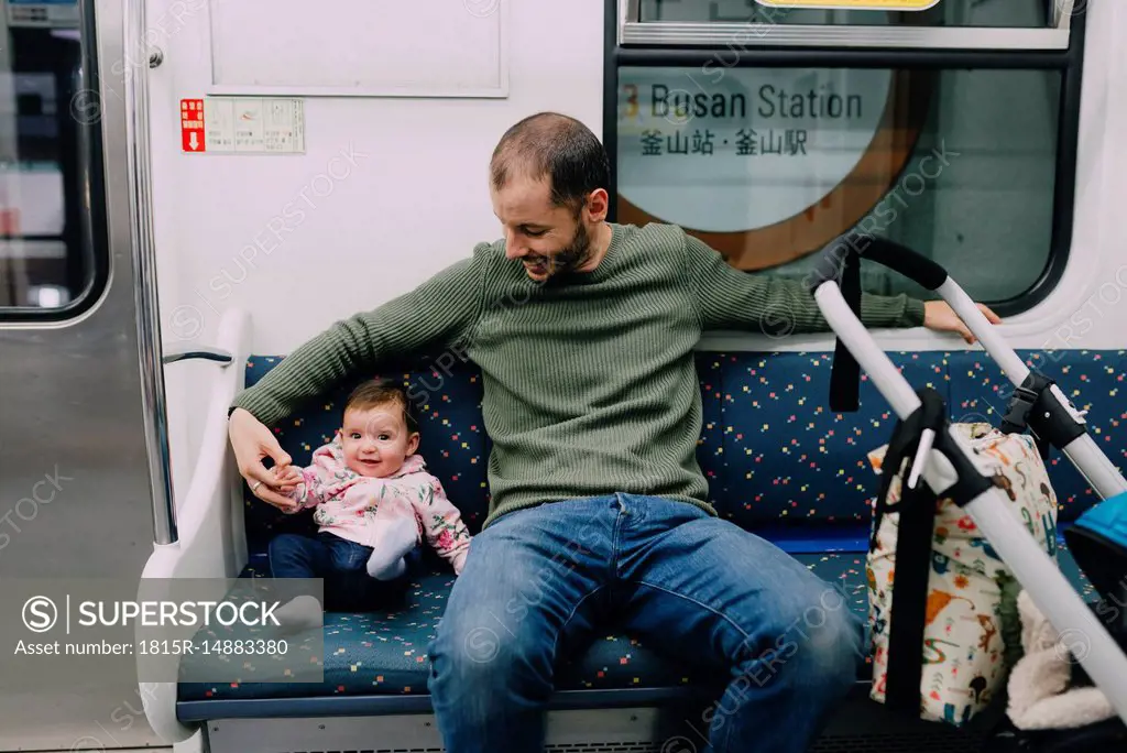 South Korea, Busan, father and baby girl traveling by subway with a stroller