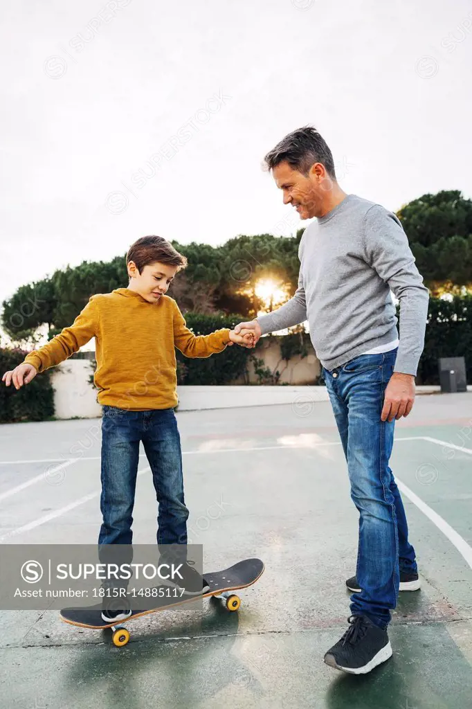 Father assisting son riding skateboard