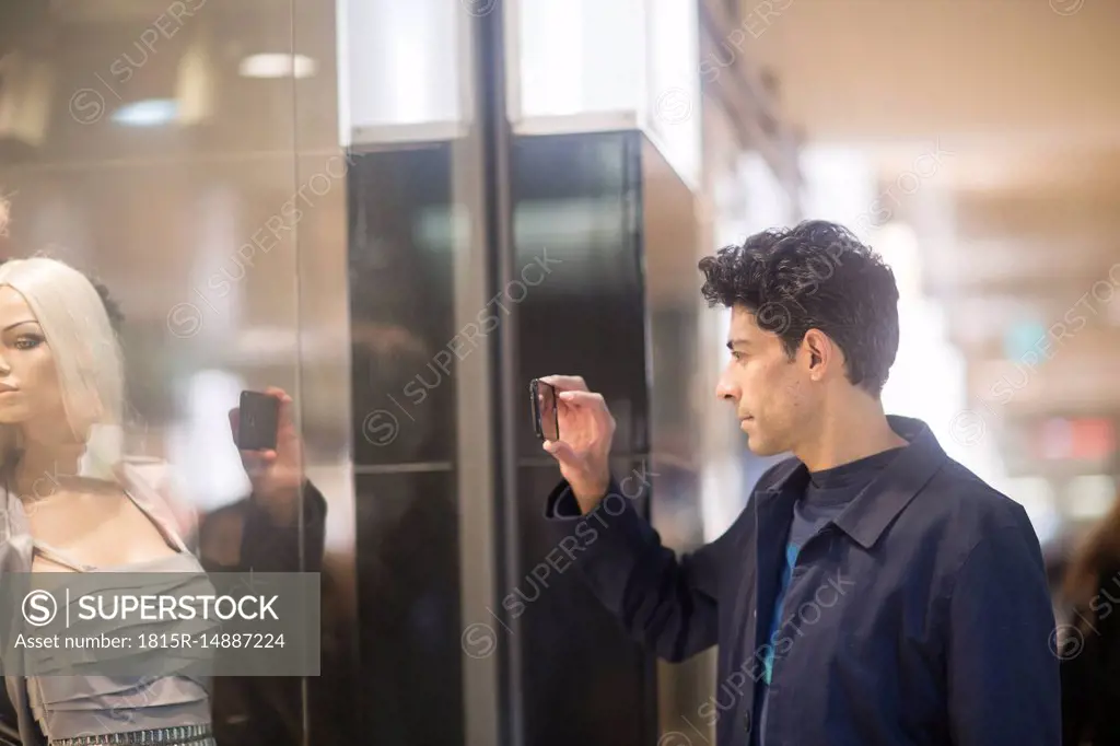 Man taking photo of display dummy with cell phone