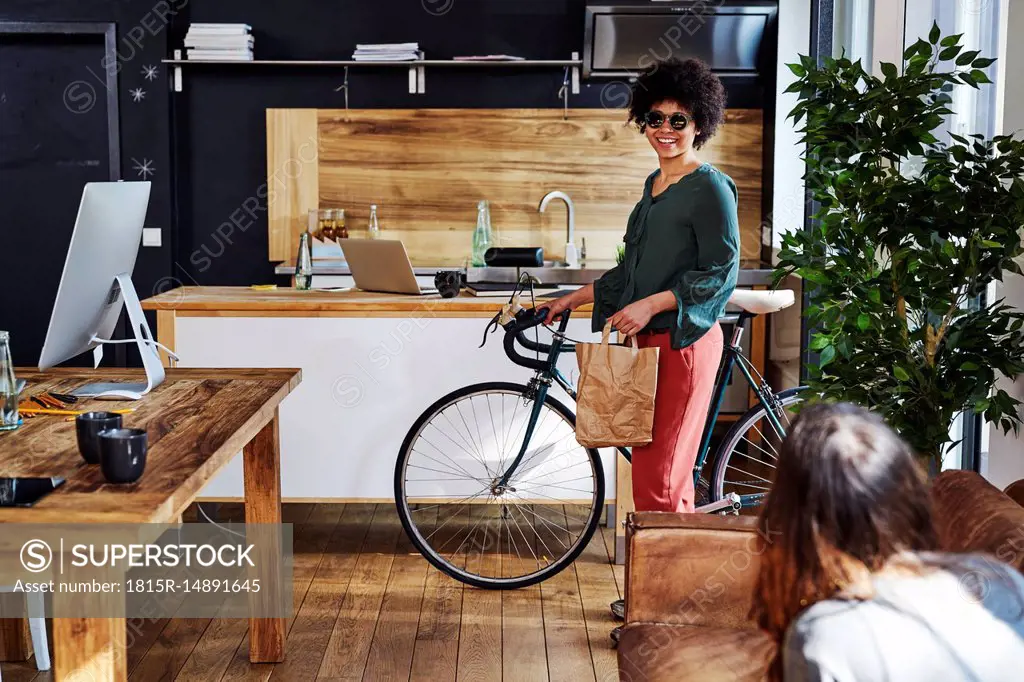 Young woman with bicycle arriving in modern office