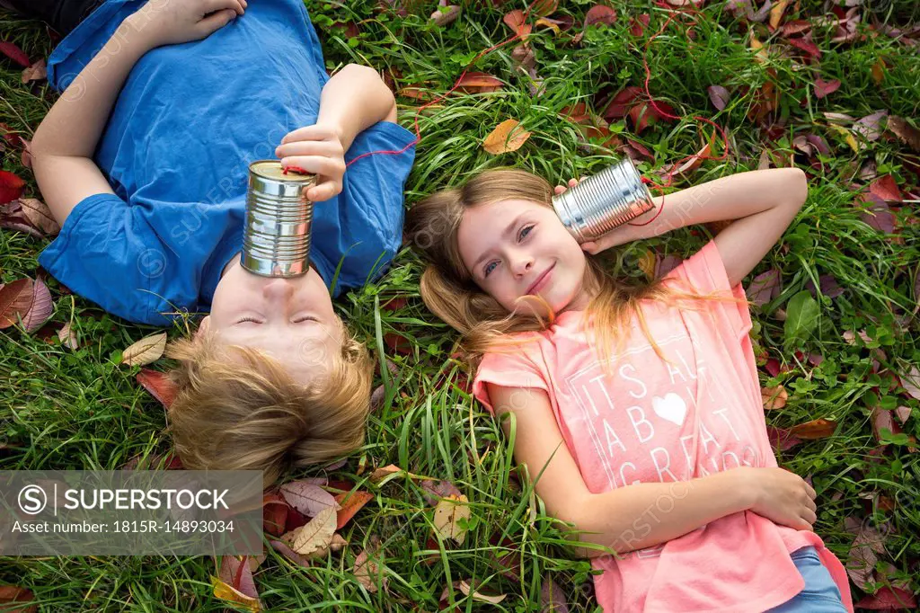 Boy and girl on a meadow having fun with tin can phone