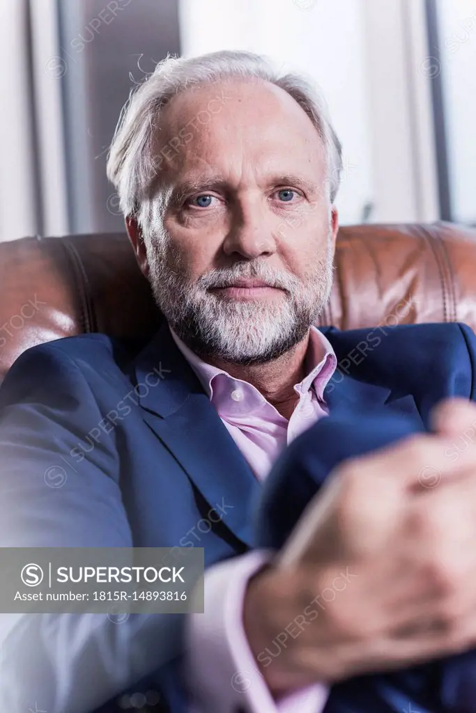 Portrait of mature businessman sitting in leather armchair