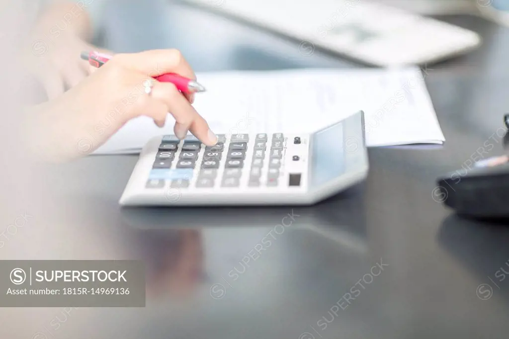 Woman at desk in office using calculator