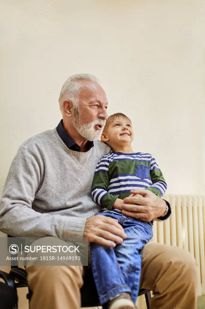 a beautiful 7 years old boy sitting next to his grandfather while