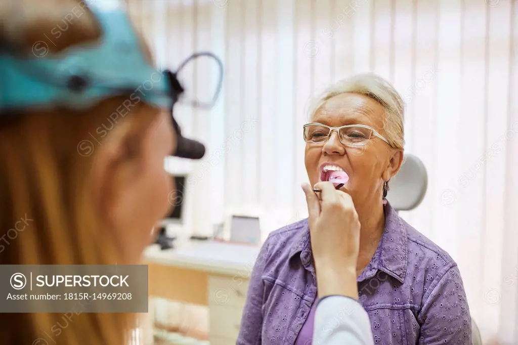 ENT physician examining mouth of a senior woman