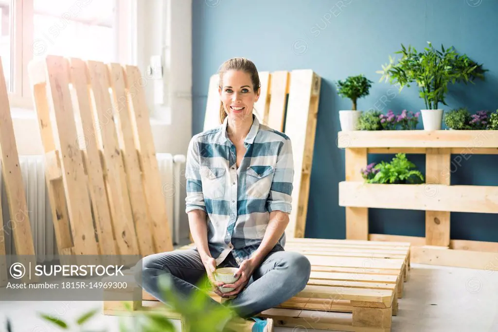 Beautiful woman taking a break from refurbishing her home with pallets, drinking coffee