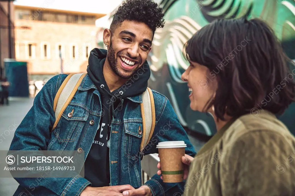 Happy young man and woman with coffee talking in the city