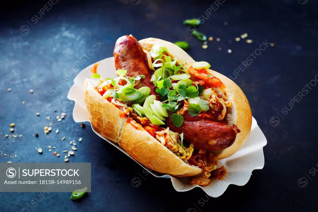 Asian hot dog, fried sausage, spicy chinese cabbage, hot chili sauce, spring onions, cress, bun
