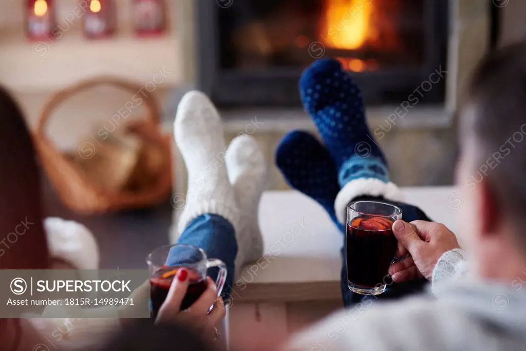 Mature couple with hot drinks in living room at the fireplace