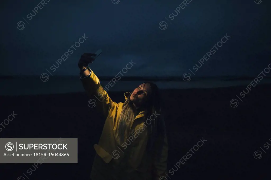 France, Brittany, Landeda, Dunes de Sainte-Marguerite, woman taking a selfie on the beach at night