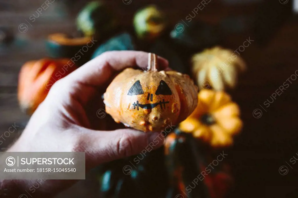 Man's hand holding painted Jack O'Lantern