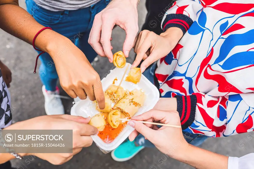 Thailand, Bangkok, Khao San Road, group of friends tasting local food on street market, close-up