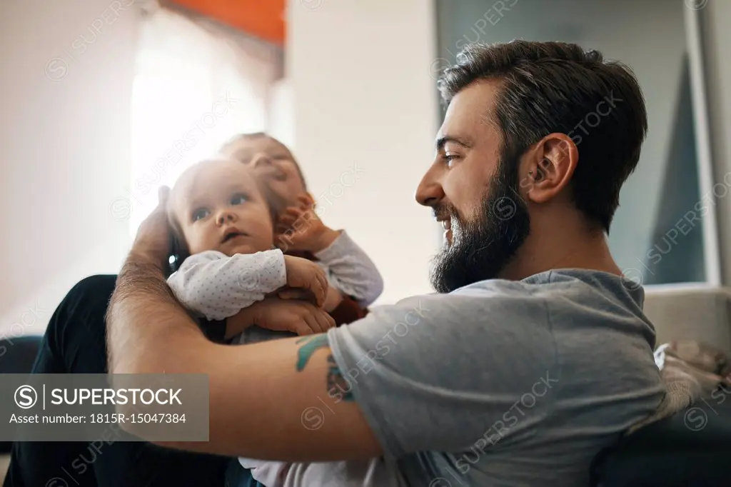 Happy father with baby girl and little son together at home