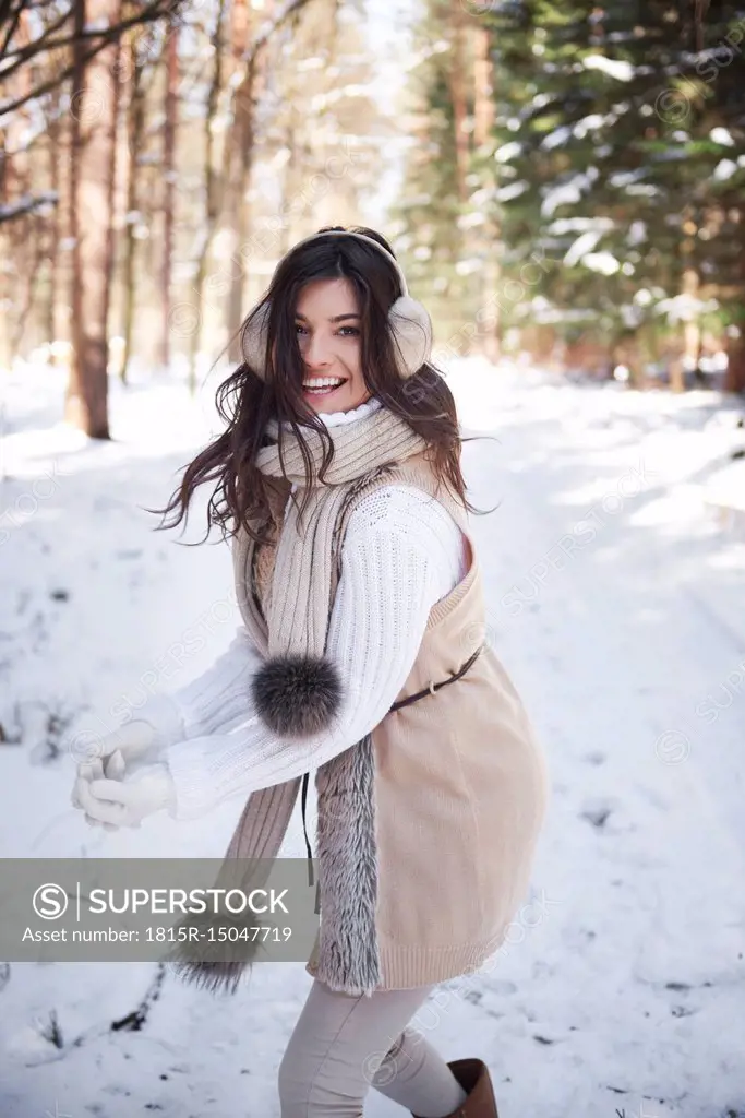 Portrait of laughing young woman having snowball fight in forest