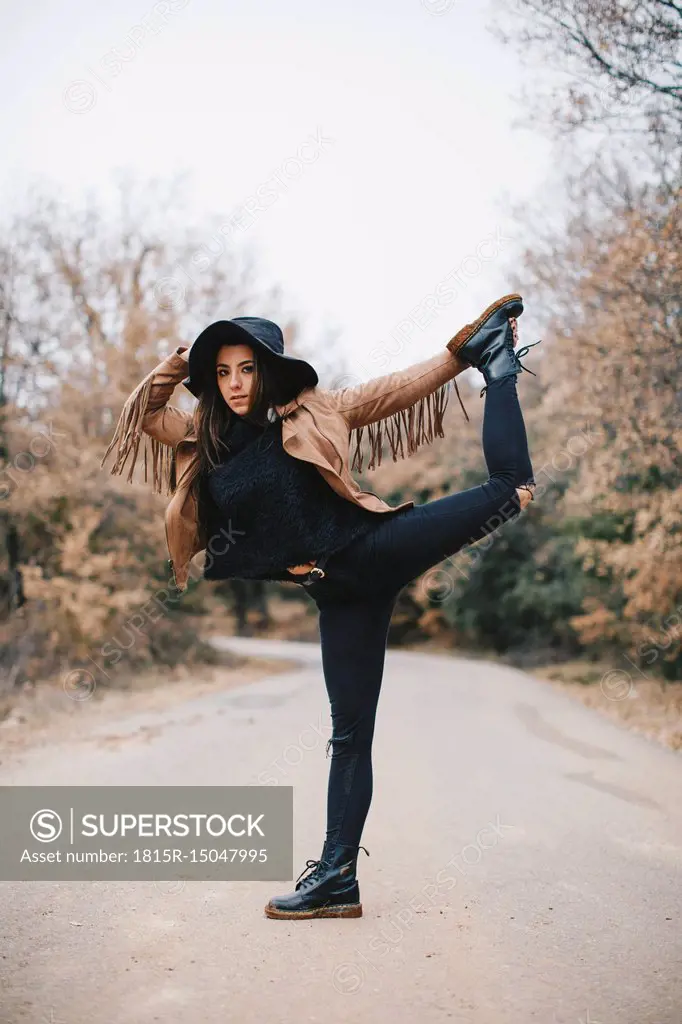 Portrait of young woman standing on one leg outdoors