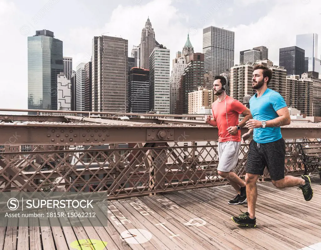 USA, New York City, two men running on Brooklyn Brige with data on the ground