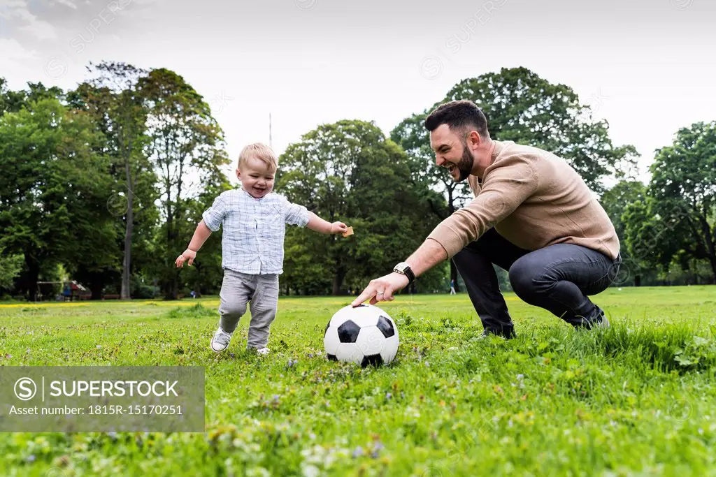 Happy father playing football with son in a park