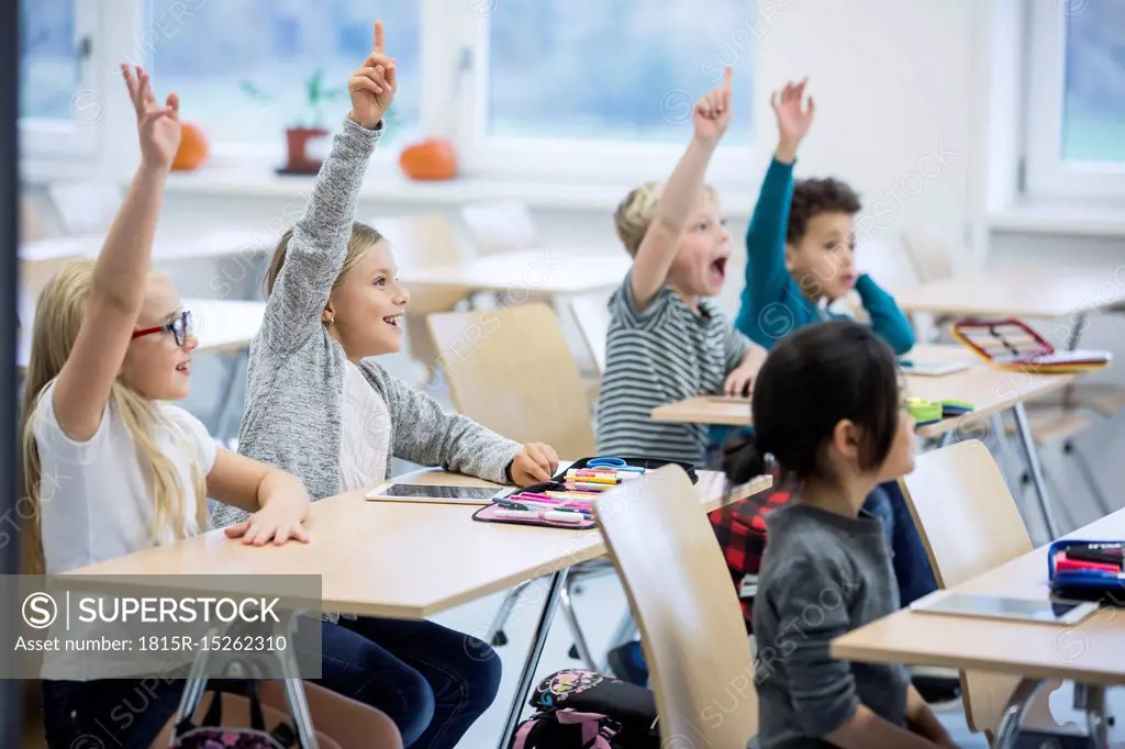 Happy pupils raising their hands in class