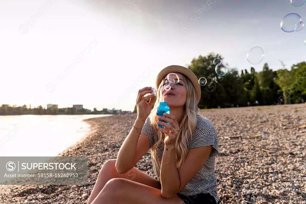 Blond woman blowing soap bubbles at riverside