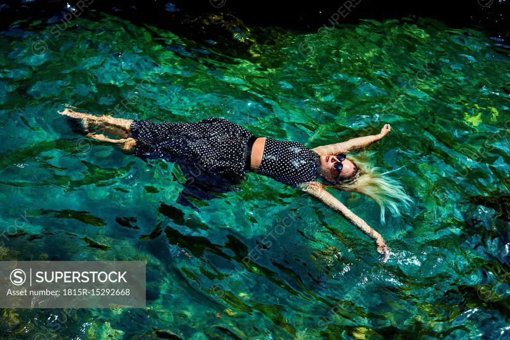 Young woman floating with dress on water in lagoon