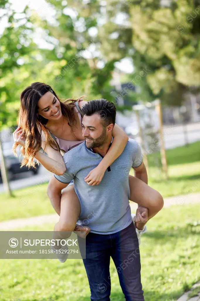 Happy man giving girlfriend a piggyback ride in park