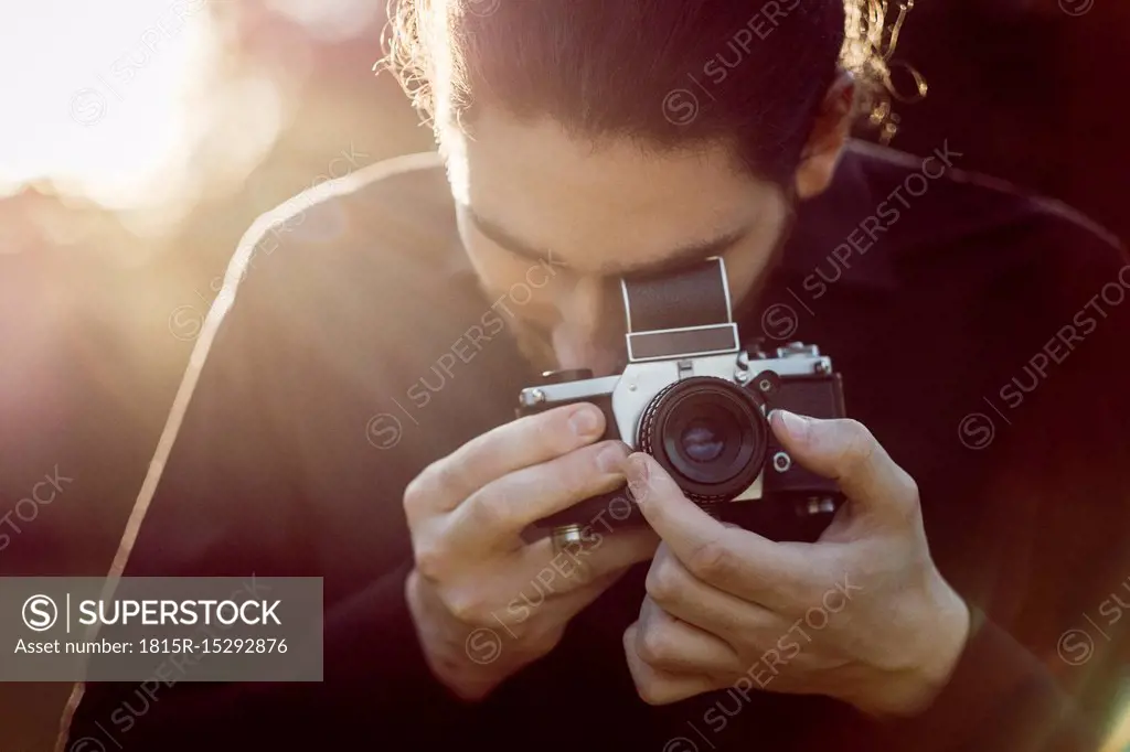 Young man photographing with analogue camera