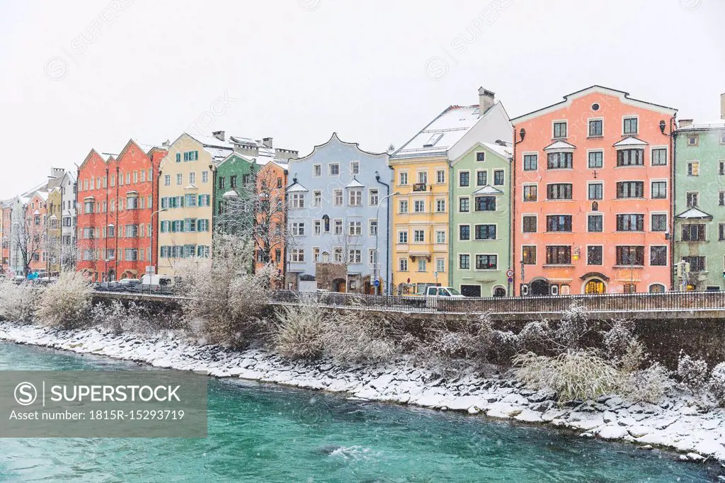 Austria, Innsbruck, row of colourful houses in winter with Inn River in the foreground