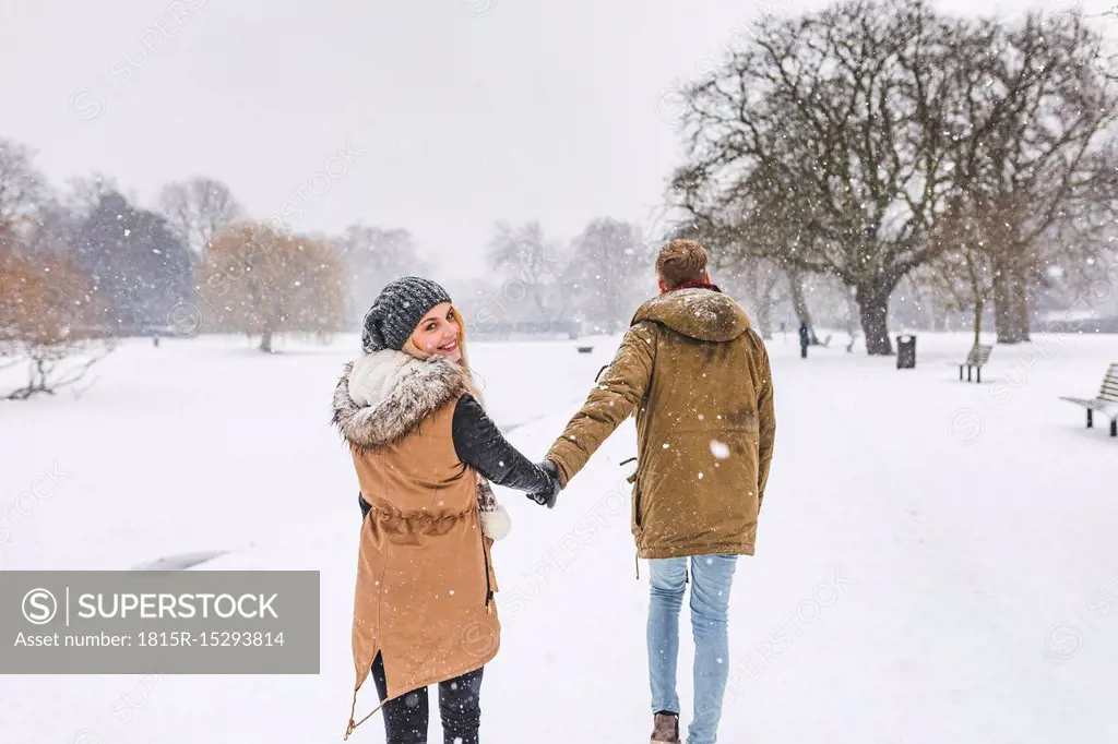 Happy teenage girl strolling with her boyfriend in park on snow day