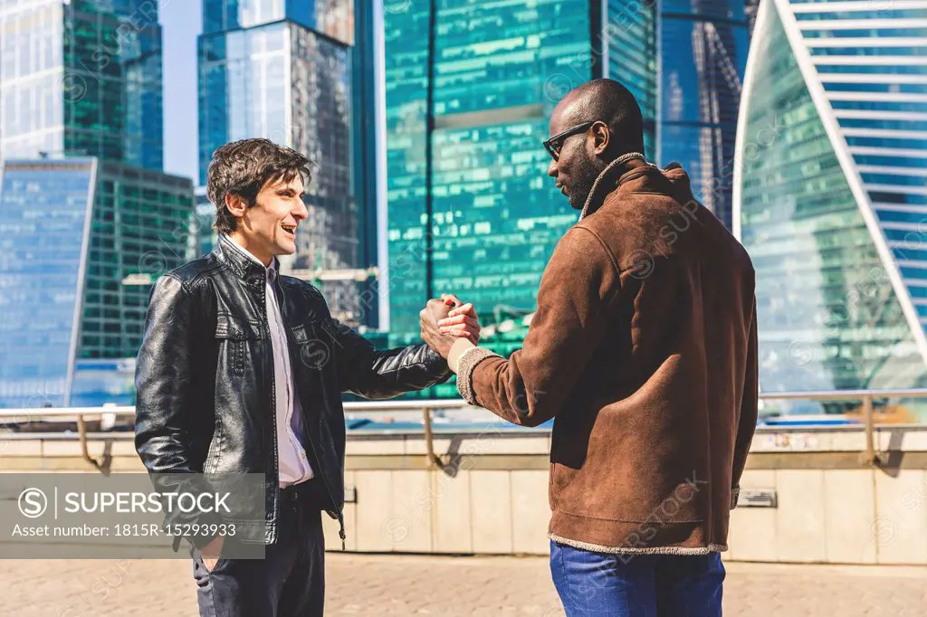 Russia, Moscow, two businessmen in front of modern office buildings