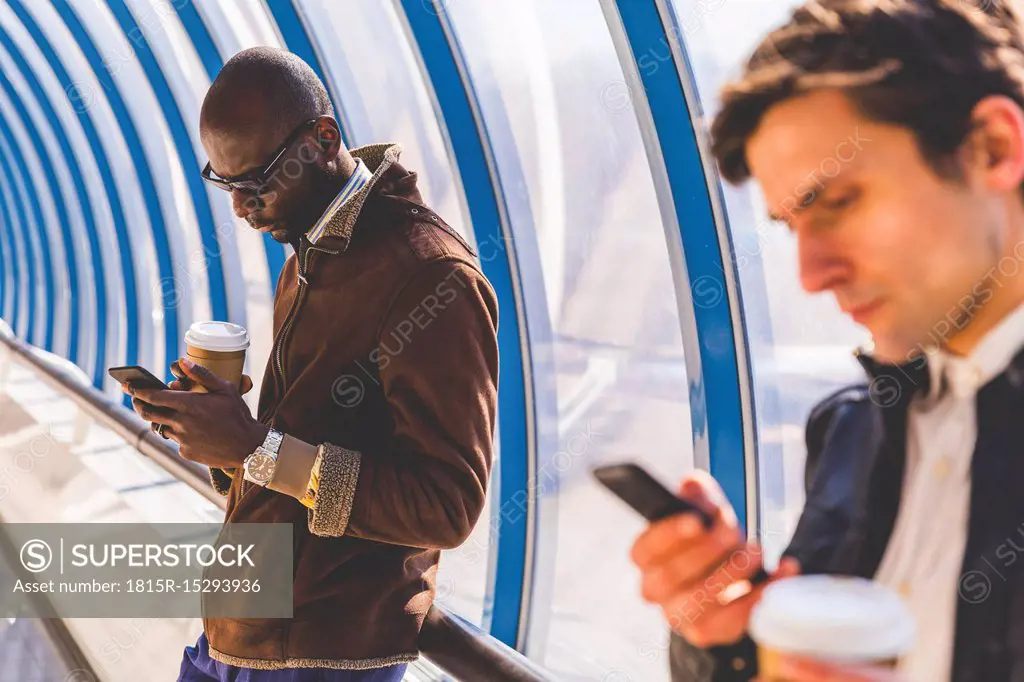 Businessmen with coffee to go using smartphone